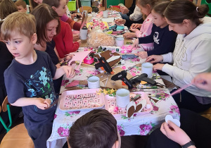 Dzieci z rodzicami podczas warsztatów wielkanocnych.