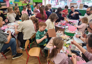 Dzieci z rodzicami podczas warsztatów wielkanocnych.