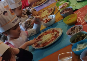 Dzieci z grupy II Żabki podczas tworzenia samodzielnie pizzy