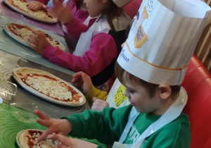 Dzieci z grupy II Żabki podczas tworzenia samodzielnie pizzy