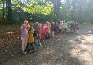 Dzieci pozują do zdjęcia ustawione parami na ścieżce w parku