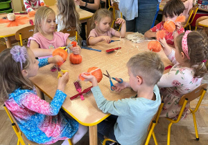 Dzieci formują swoje dynie ze sznurków przy stolikach